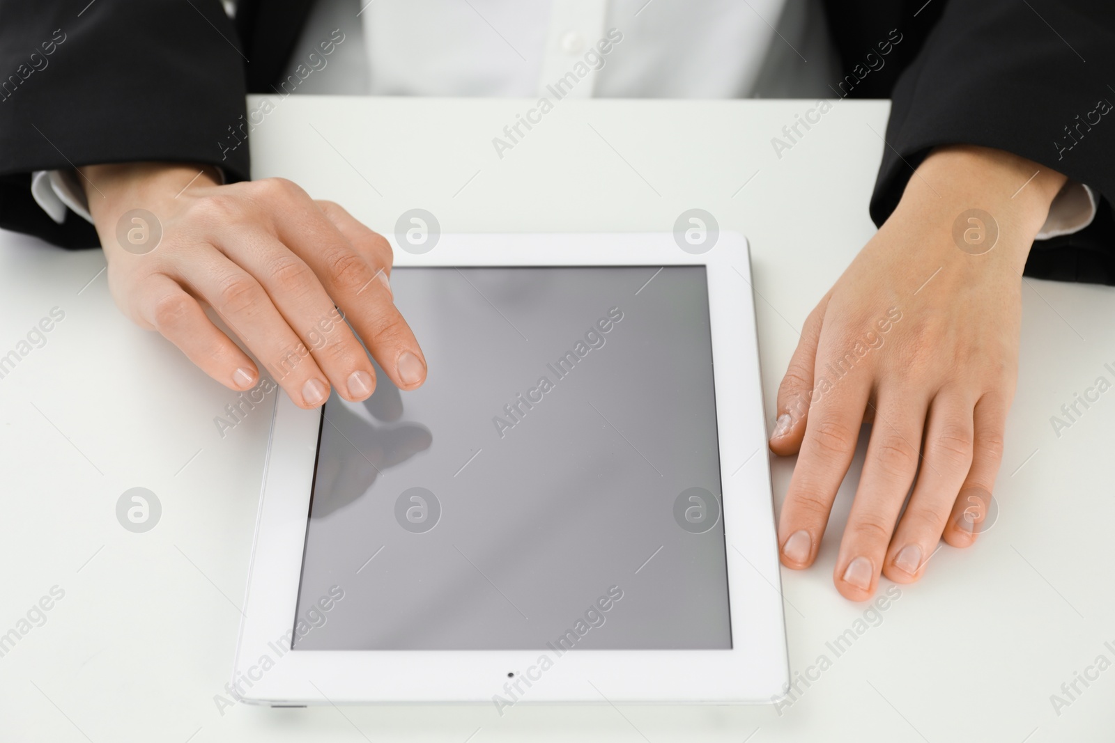 Photo of Businesswoman using tablet at white table indoors, closeup. Modern technology