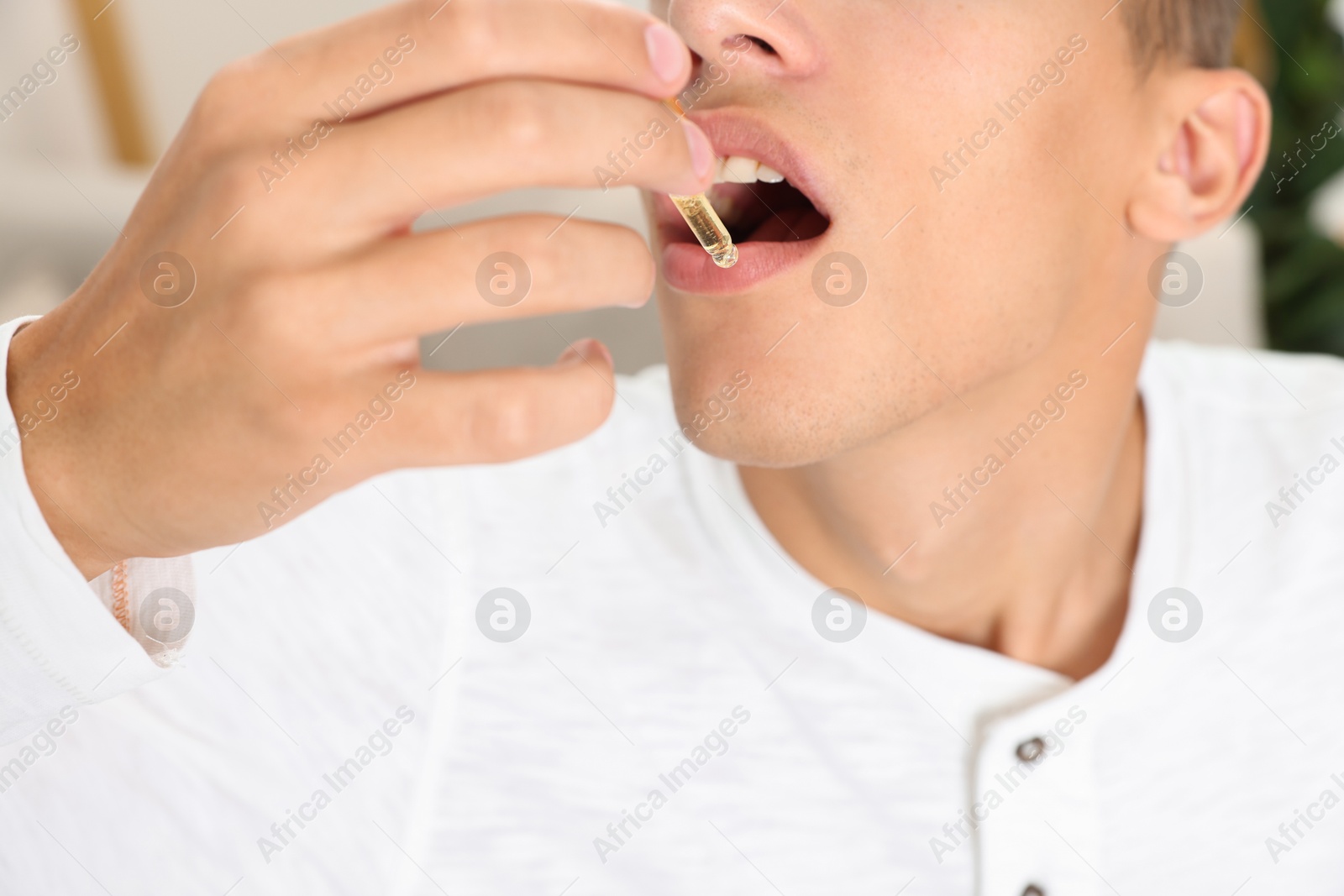 Photo of Young man taking CBD tincture indoors, closeup