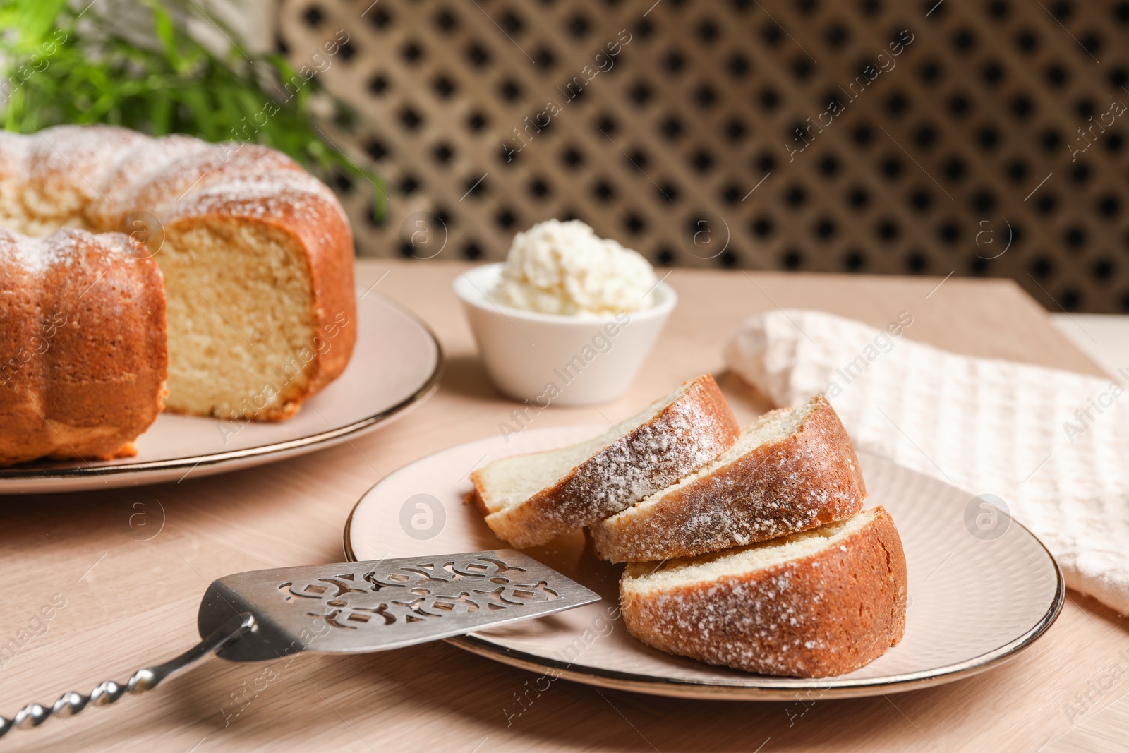 Photo of Pieces of freshly baked sponge cake, server and ice cream on wooden table, closeup