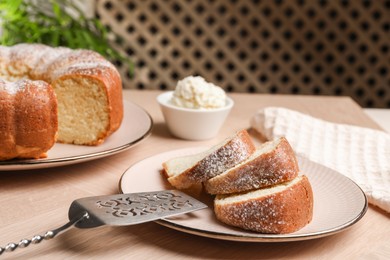 Photo of Pieces of freshly baked sponge cake, server and ice cream on wooden table, closeup