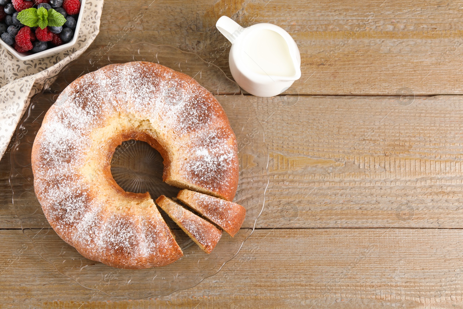 Photo of Freshly baked sponge cake, milk and berries on wooden table, top view. Space for text