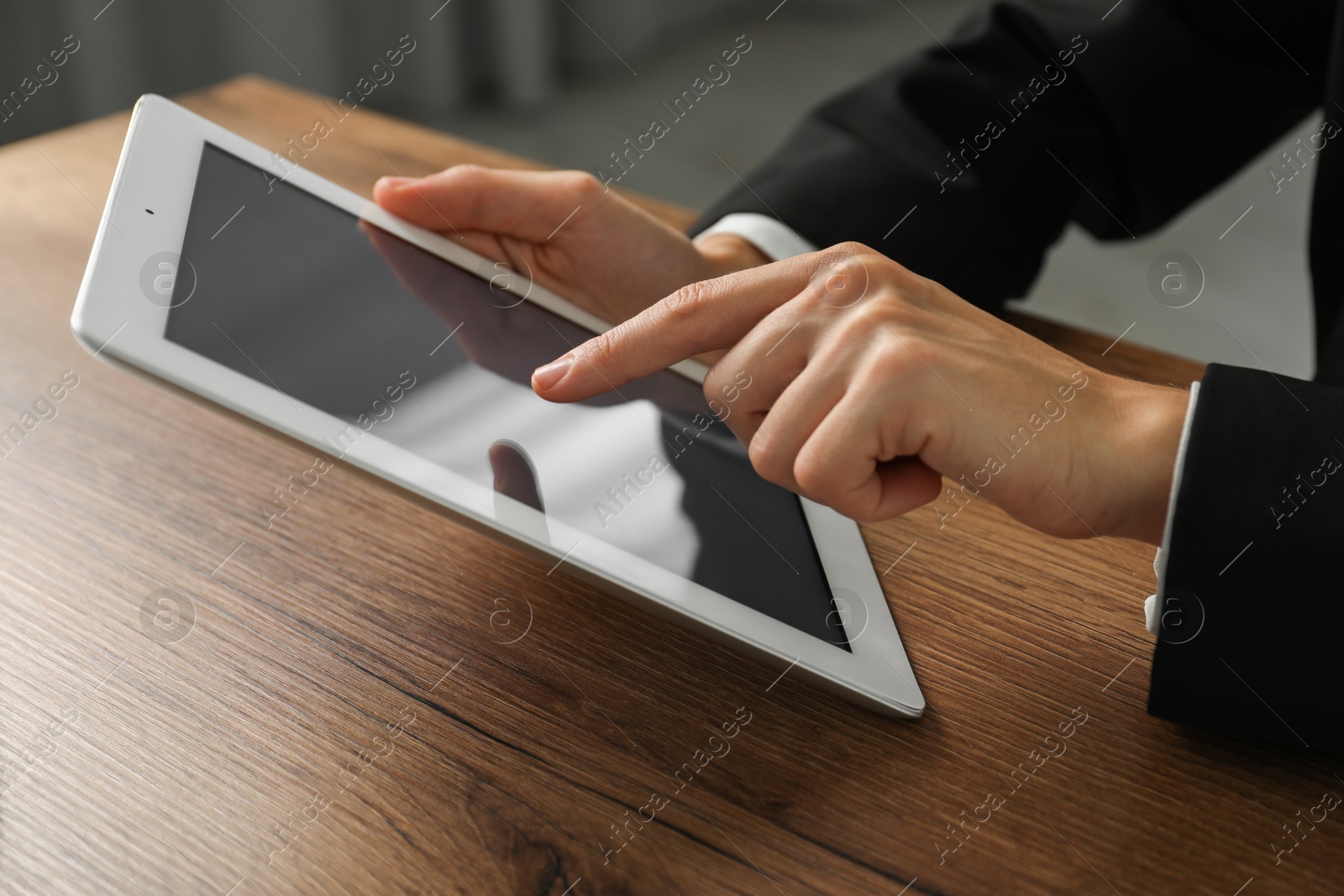 Photo of Businesswoman using tablet at wooden table indoors, closeup. Modern technology