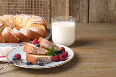 Photo of Pieces of freshly baked sponge cake, berries and milk on wooden table, space for text