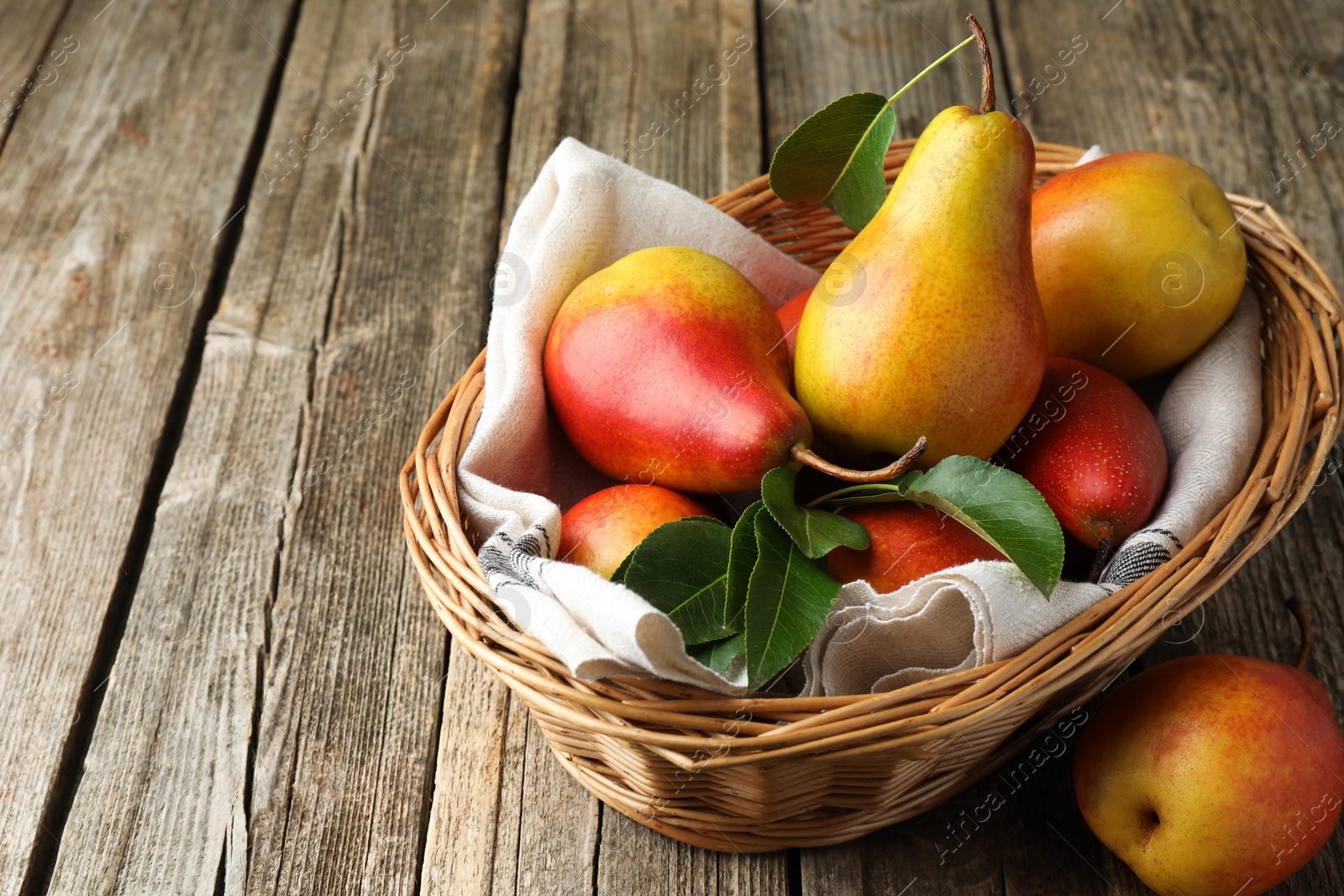 Photo of Ripe juicy pears in wicker basket on wooden table