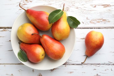 Photo of Ripe juicy pears in bowl on light wooden table, top view