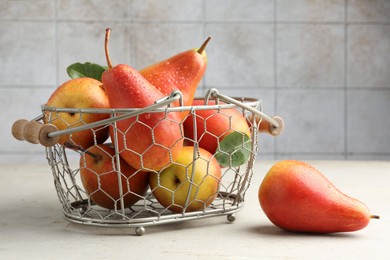 Photo of Ripe juicy pears in metal basket on grey textured table