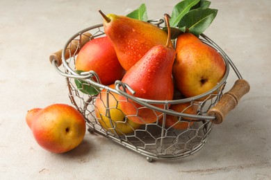 Photo of Ripe juicy pears in metal basket on grey textured table