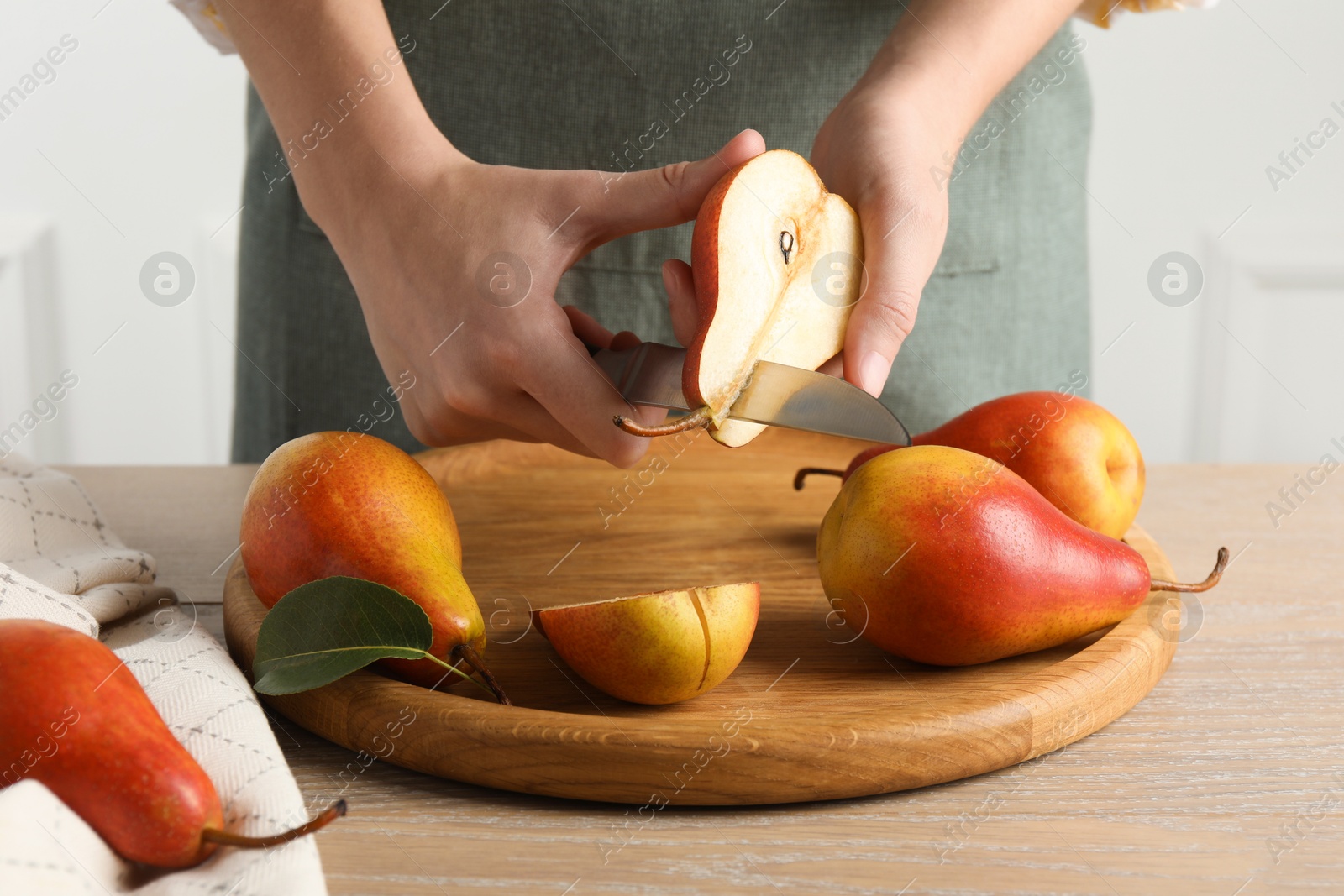 Photo of Woman cutting pear at wooden table, closeup