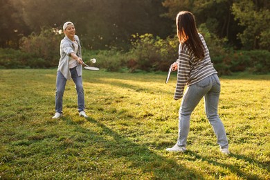 Photo of Young man and woman playing badminton in park on sunny day, selective focus