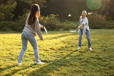 Photo of Young man and woman playing badminton in park on sunny day, selective focus