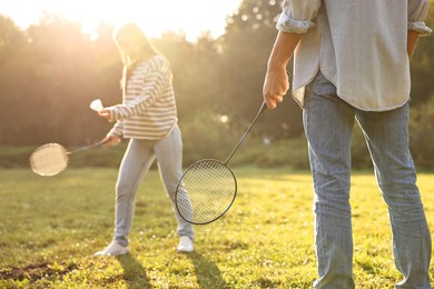 Photo of Young woman and man playing badminton in park on sunny day, selective focus