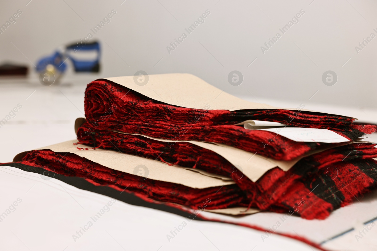 Photo of Pieces of fabric and measurements on white table in professional workshop, closeup