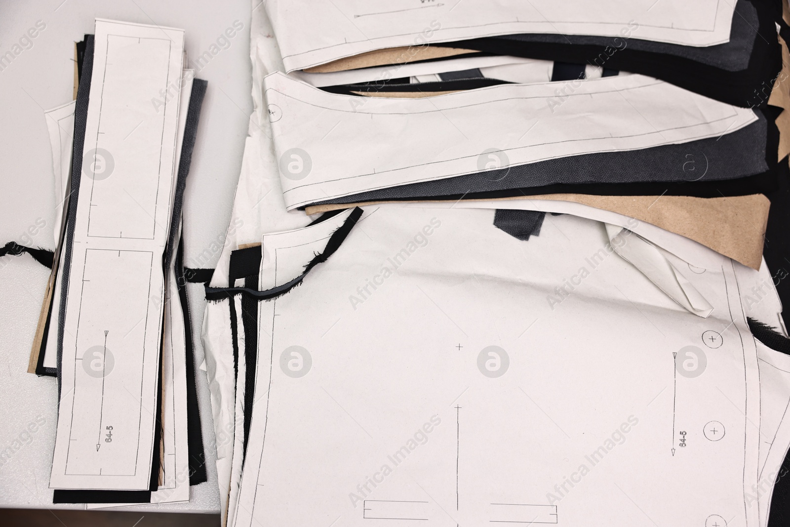 Photo of Pieces of fabric and measurements on white table in professional workshop, top view