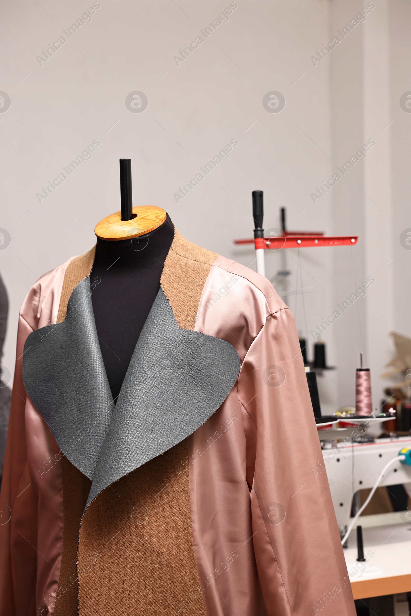 Photo of Professional workshop with sewing machine, coat and mannequin