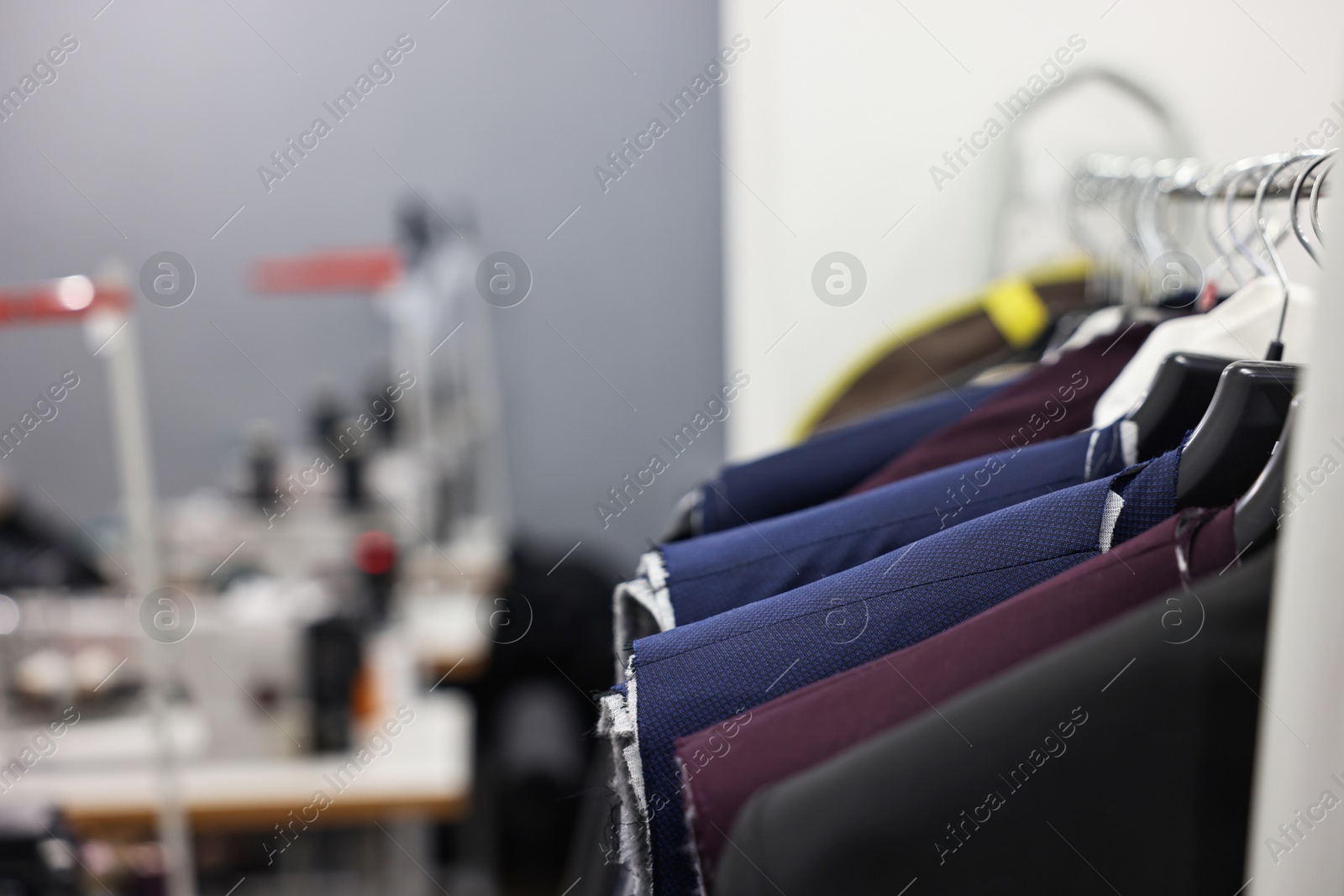 Photo of Clothes hanging from rack in professional workshop, closeup