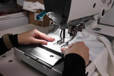 Photo of Woman working with sewing machine in professional workshop, closeup