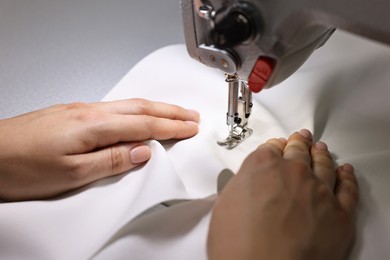 Photo of Woman working with sewing machine in professional workshop, closeup