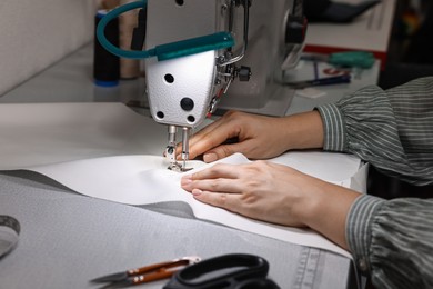 Photo of Woman working with sewing machine in professional workshop, closeup