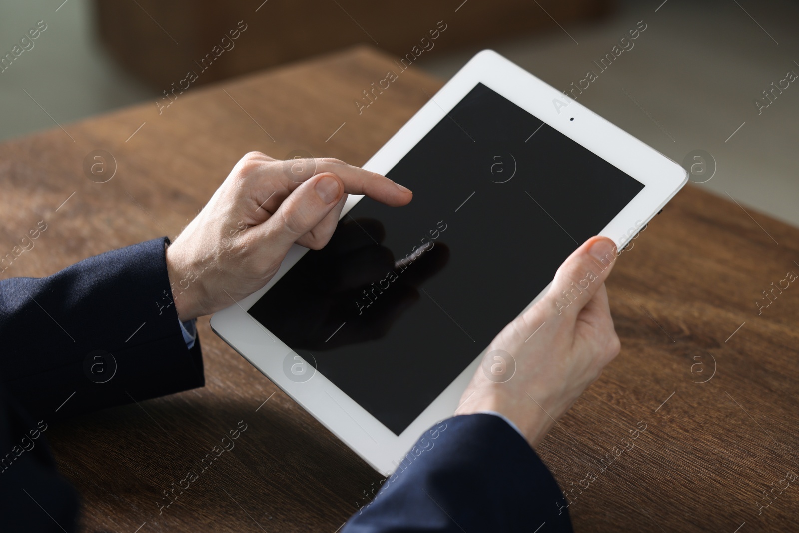 Photo of Businessman using tablet at wooden table, closeup. Modern technology