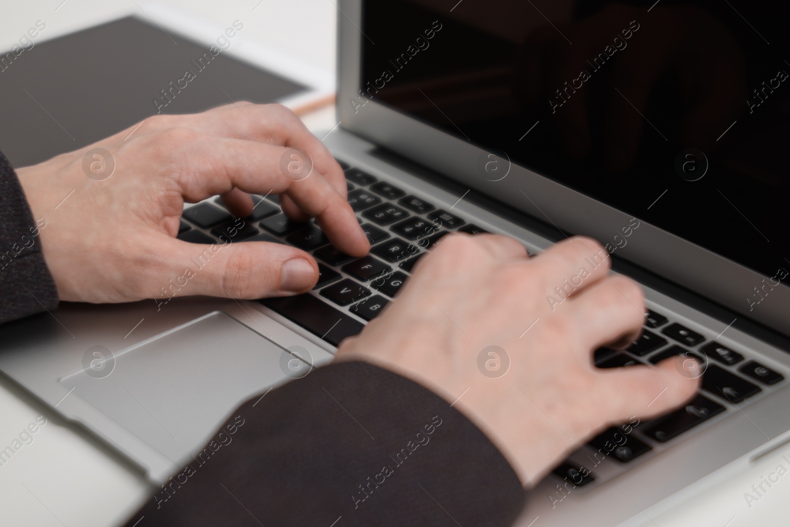 Photo of Businessman using laptop at white table indoors, closeup. Modern technology