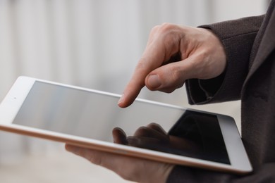 Photo of Businessman using tablet indoors, closeup. Modern technology