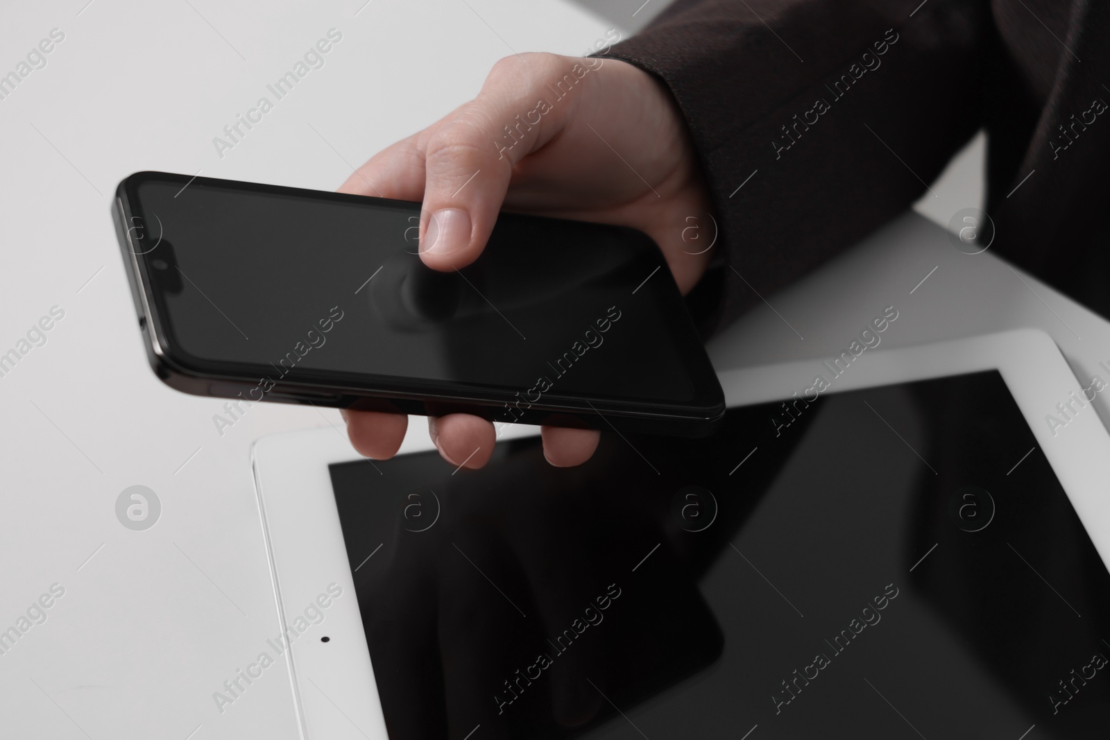 Photo of Businessman using smartphone at white table with tablet, closeup. Modern technology