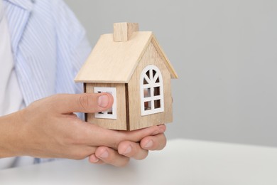 Photo of Real estate insurance. Man with wooden house figure at light table, closeup. Space for text