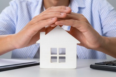 Photo of Real estate insurance. Man with wooden house figure at light table, closeup