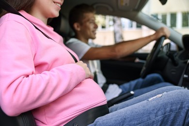 Smiling pregnant woman travelling with her husband by car, closeup