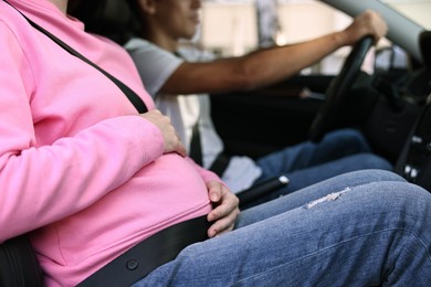 Pregnant woman travelling with her husband by car, closeup