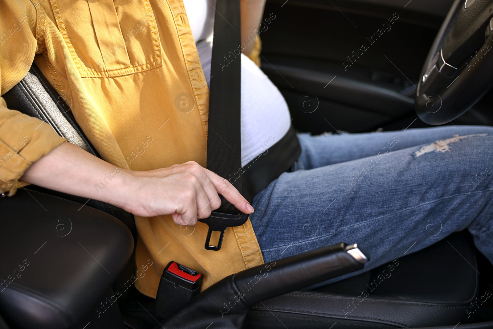 Photo of Pregnant woman fastening safety belt in car, closeup