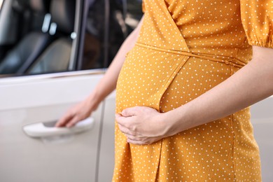 Photo of Pregnant woman opening car door outdoors, closeup