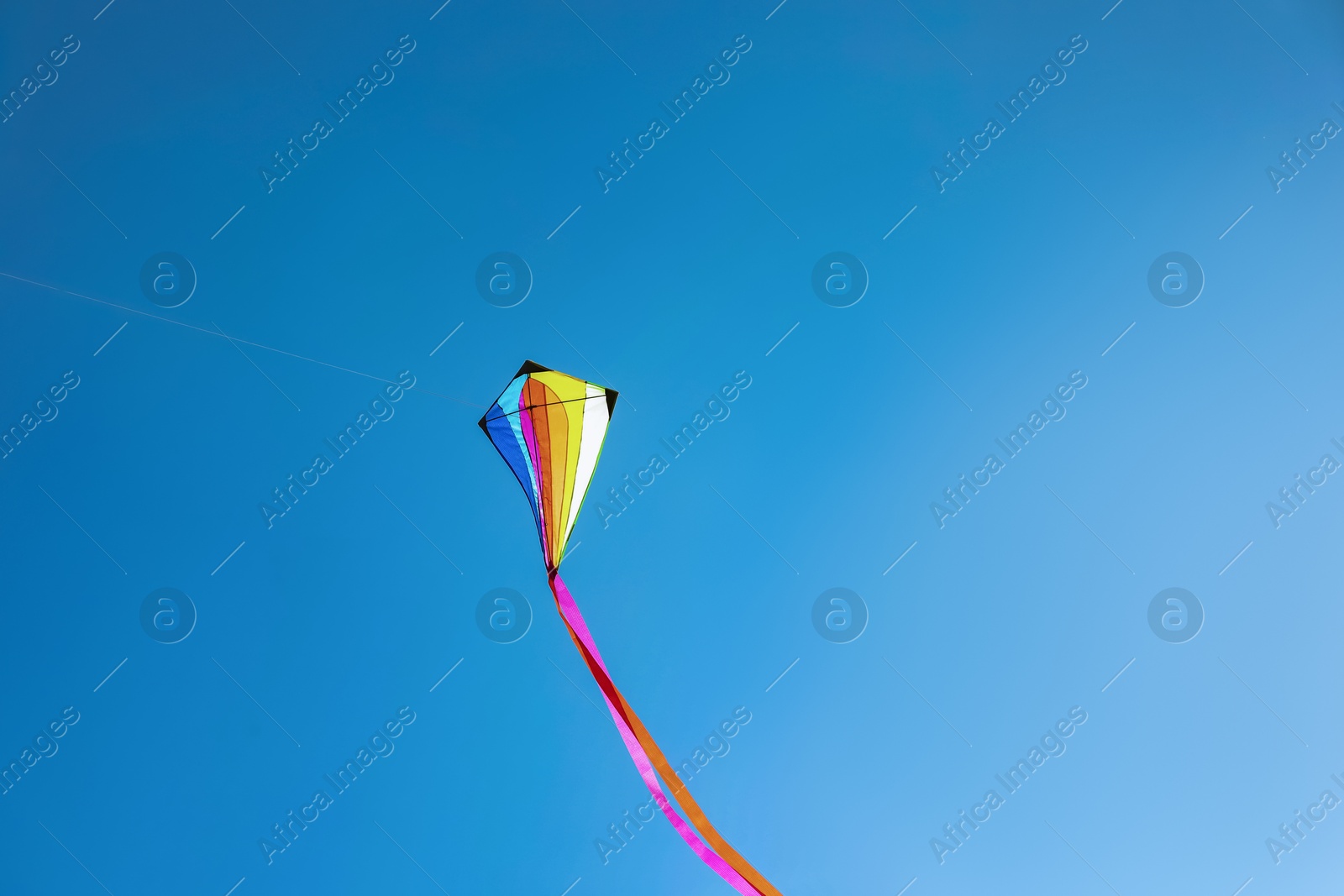 One colorful kite flying in sky on sunny day Photo of One colorful kite flying in sky on sunny day