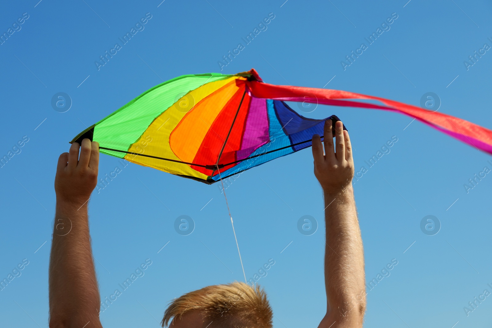 Man with kite against blue sky, closeup Photo of Man with kite against blue sky, closeup