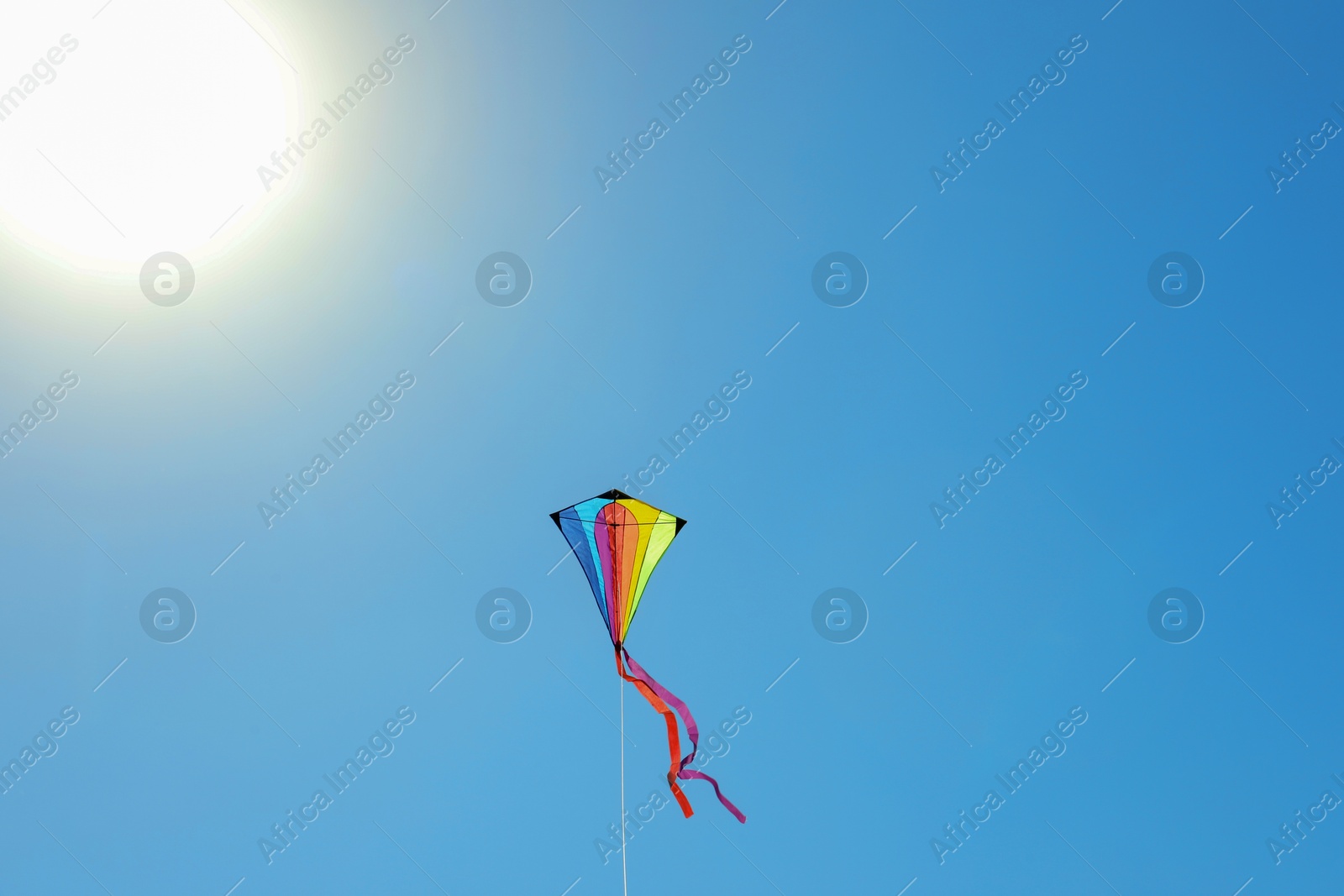 One colorful kite flying in blue sky on sunny day. Space for text Photo of One colorful kite flying in blue sky on sunny day. Space for text