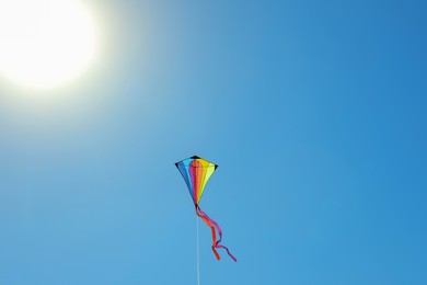 Photo of One colorful kite flying in blue sky on sunny day. Space for text
