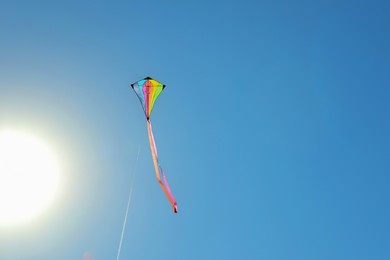 Photo of One colorful kite flying in blue sky on sunny day. Space for text