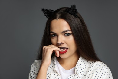 Photo of Attractive woman with cat makeup and ears on grey background