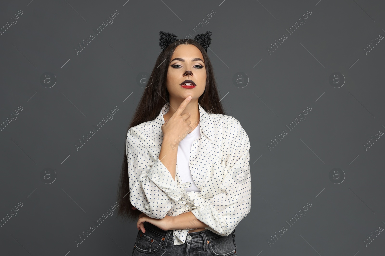 Photo of Attractive woman with cat makeup and ears on grey background