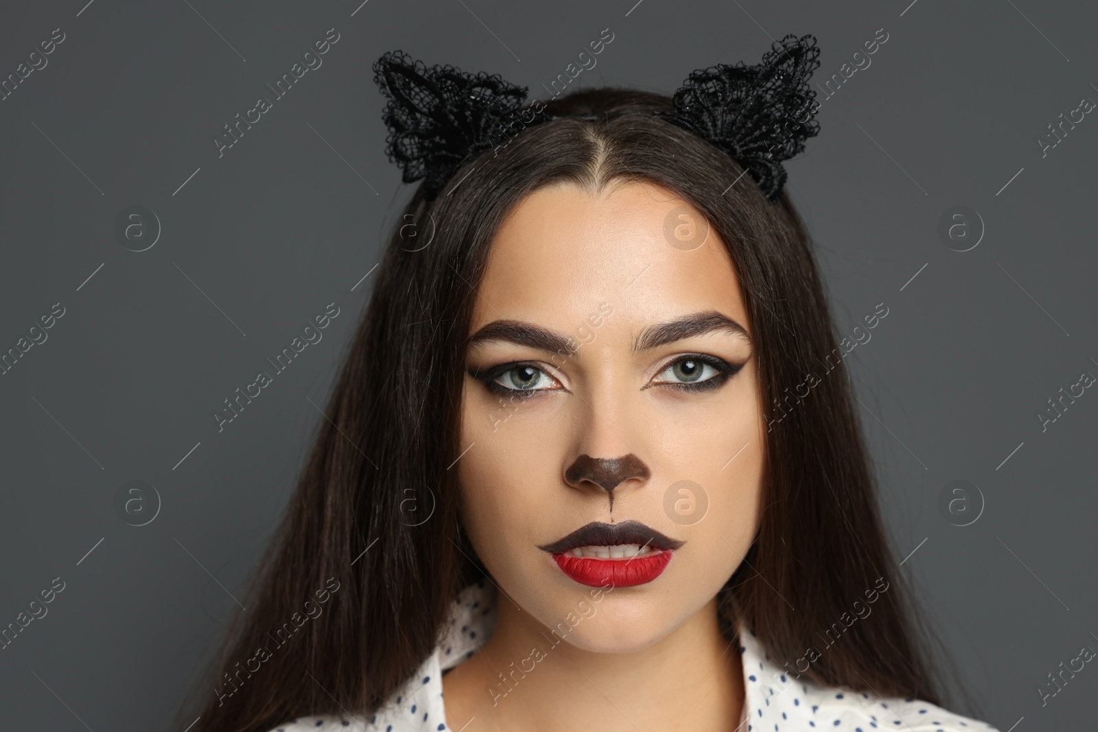 Photo of Attractive woman with cat makeup and ears on grey background