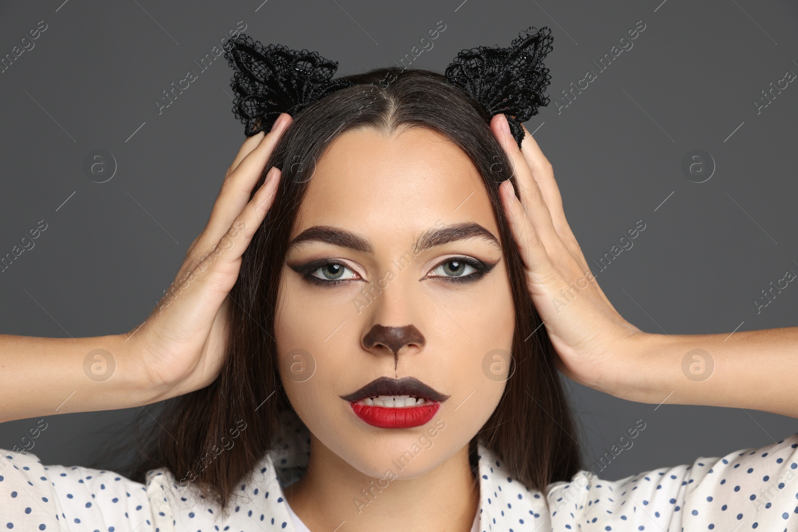 Photo of Attractive woman with cat makeup and ears on grey background