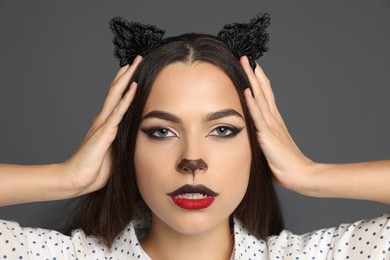 Attractive woman with cat makeup and ears on grey background