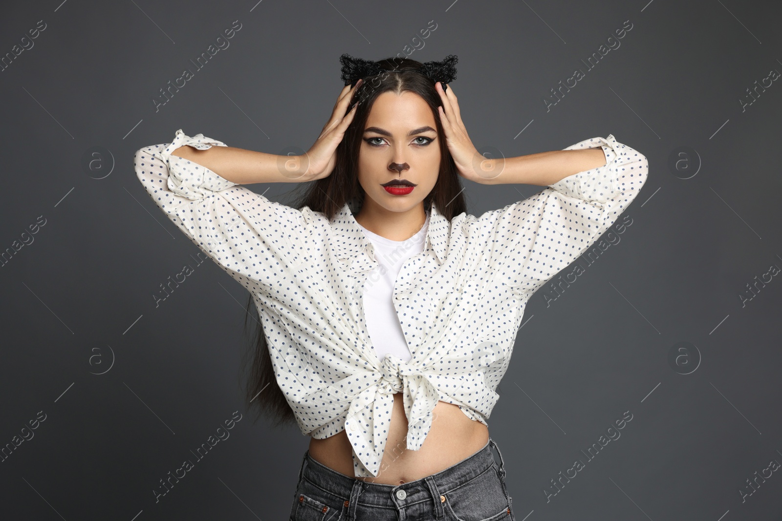 Photo of Attractive woman with cat makeup and ears on grey background