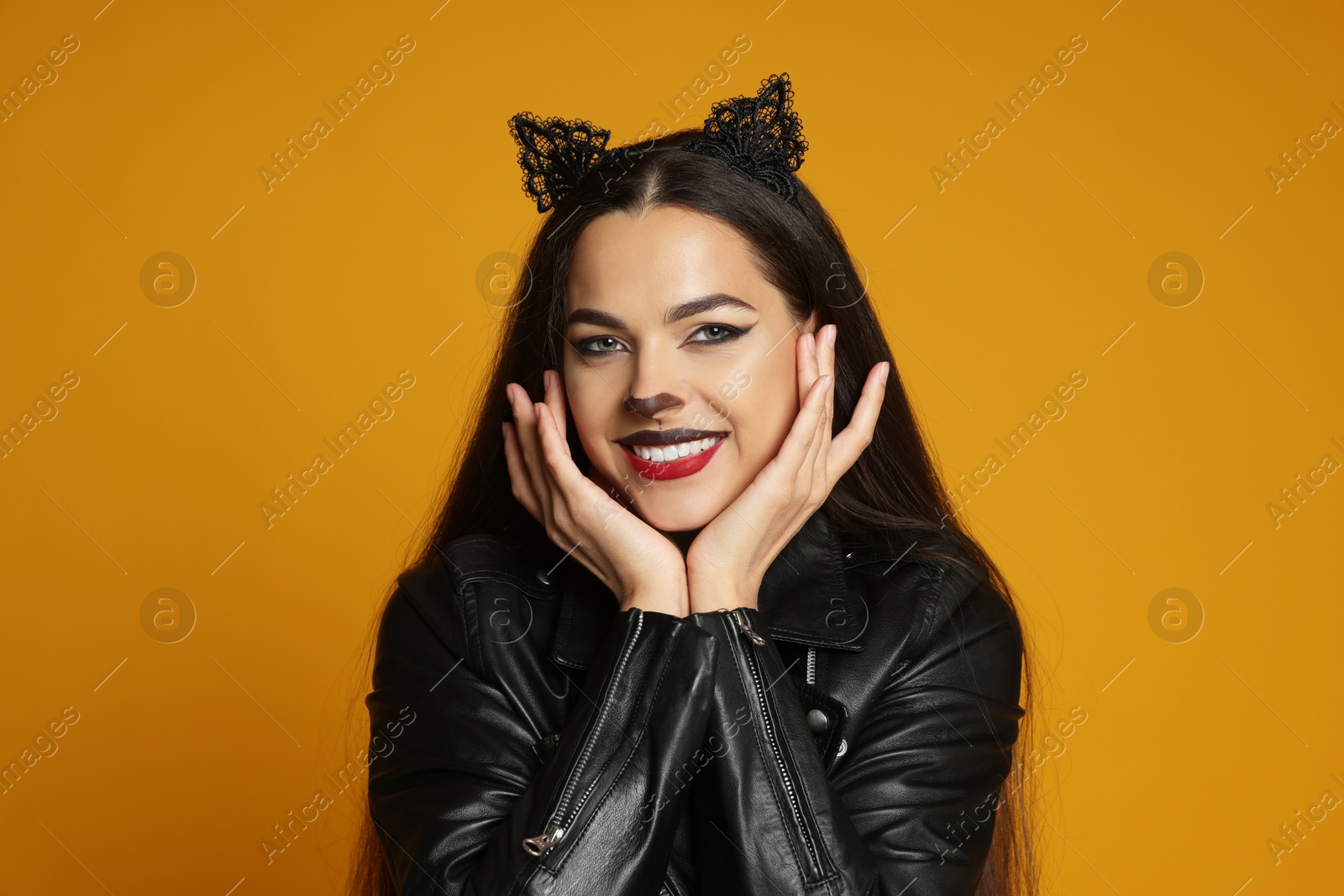 Photo of Woman with cat makeup and ears in leather jacket on orange background