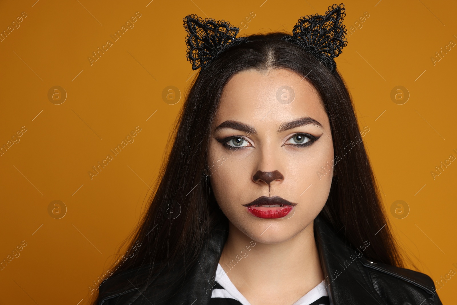 Photo of Woman with cat makeup and ears on orange background