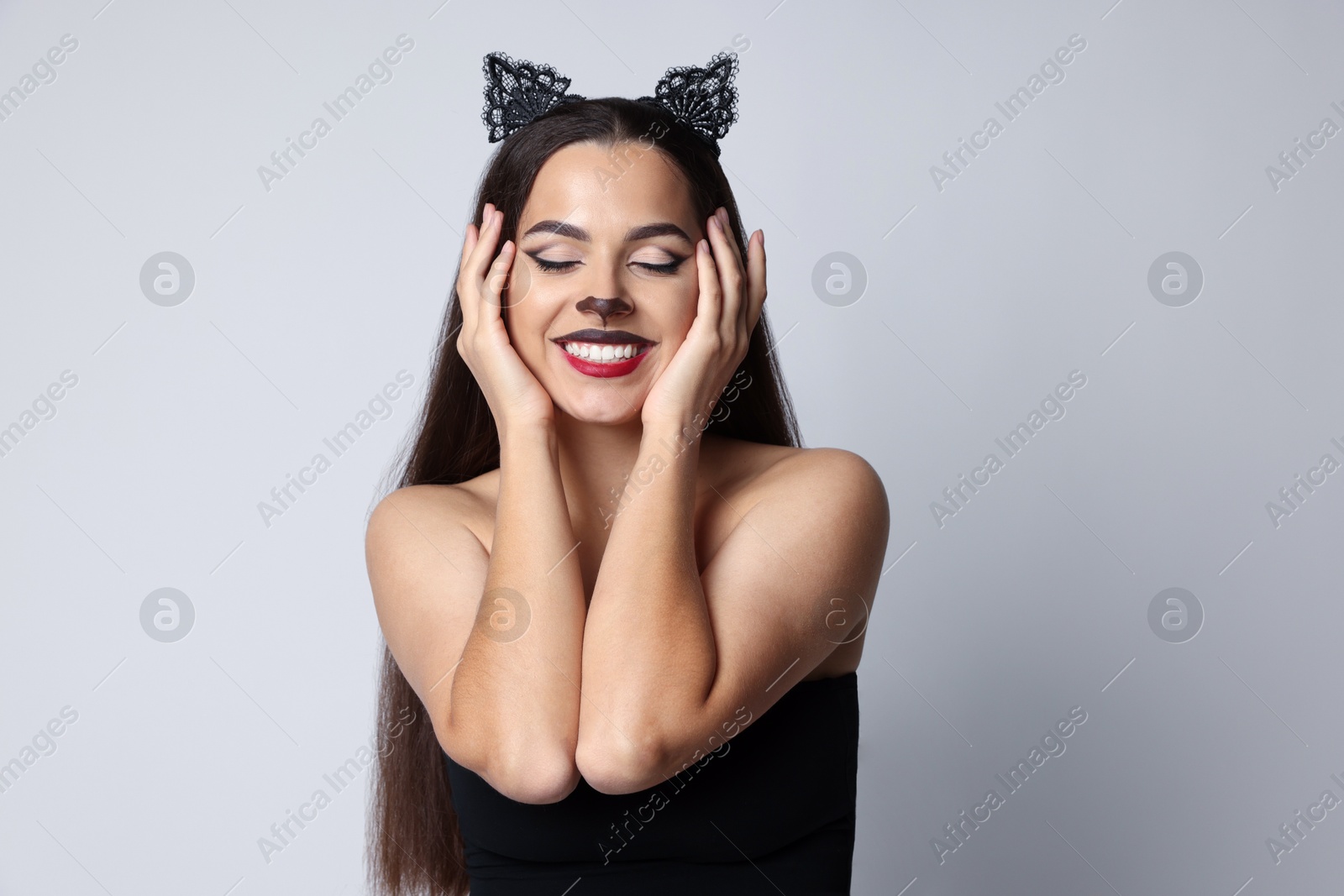 Photo of Smiling woman with cat makeup and ears on white background