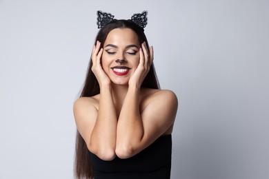 Photo of Smiling woman with cat makeup and ears on white background