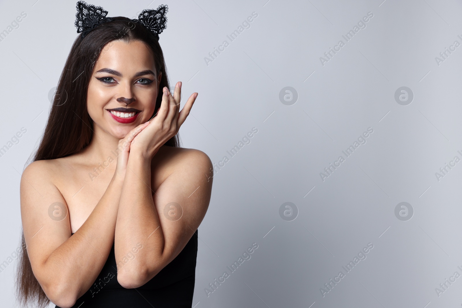 Photo of Smiling woman with cat makeup and ears on white background. Space for text