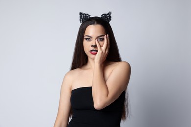 Photo of Attractive woman with cat makeup and ears on white background