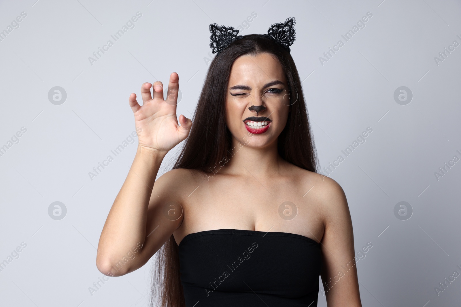 Photo of Playful woman with cat makeup and ears on white background